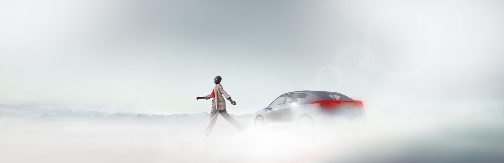 Person walking in front of a car through a foggy landscape