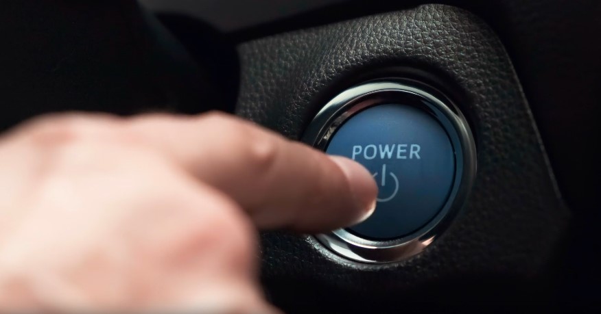 Close-up of a finger pressing a car engine start-stop button