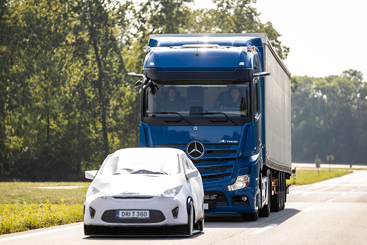 Blue truck following a white test vehicle on a road