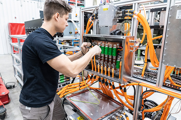 Technician performing system integration on electronic equipment with orange power cables