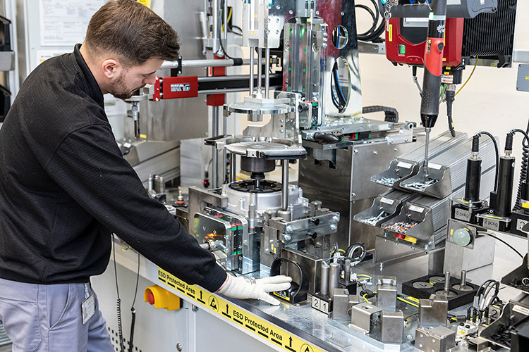 Factory worker monitoring machinery during automotive part assembly