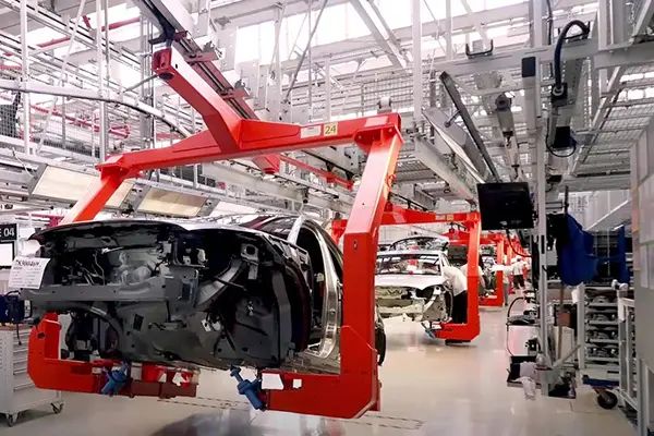 Car bodies suspended on a red overhead conveyor system in an automotive assembly plant
